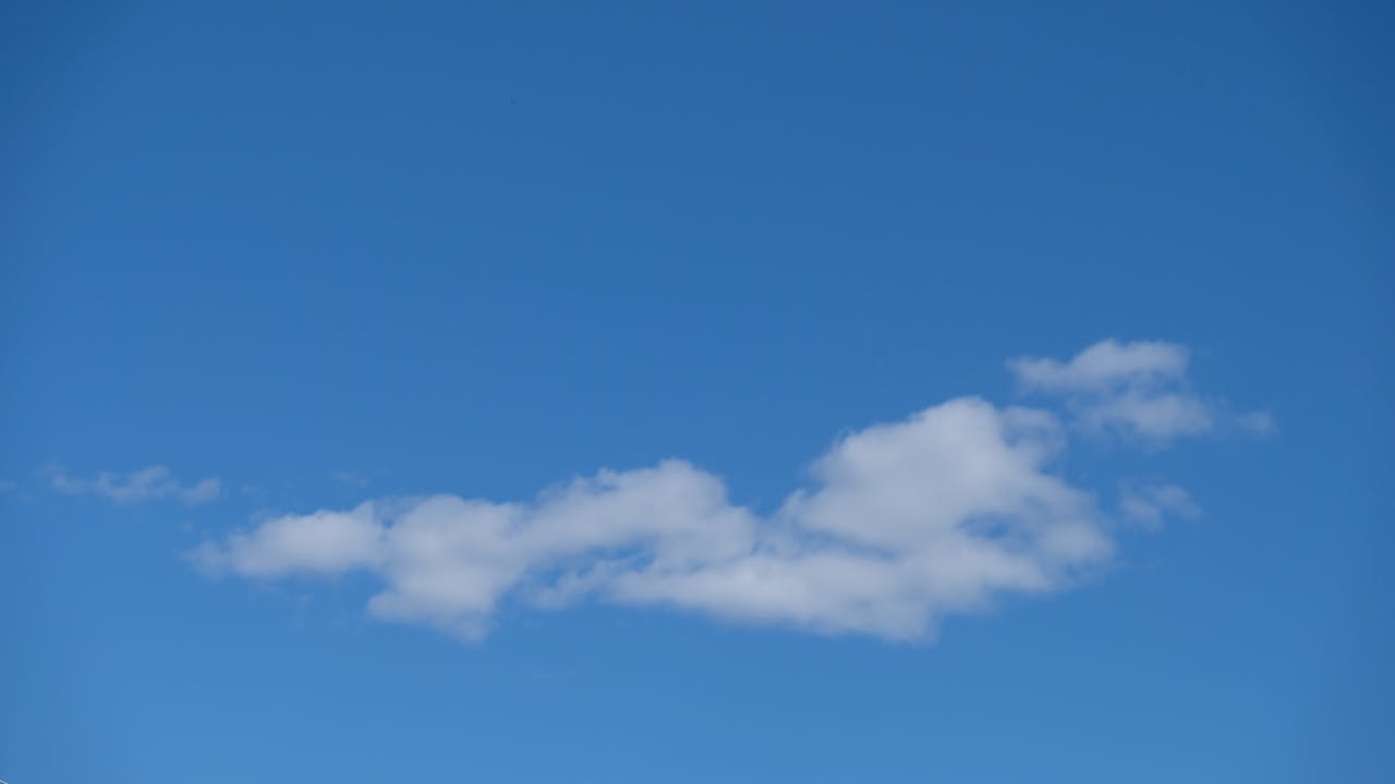 Serene view of fluffy white clouds floating in a bright blue sky, ideal for backgrounds.